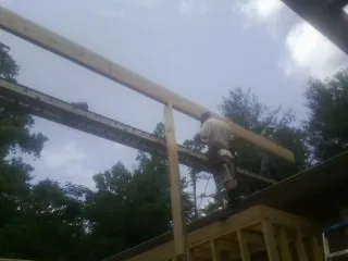 Carpenter setting a ridge beam over a new addition frame — Ice Dam Removal by Roofing Brothers in Enfield
